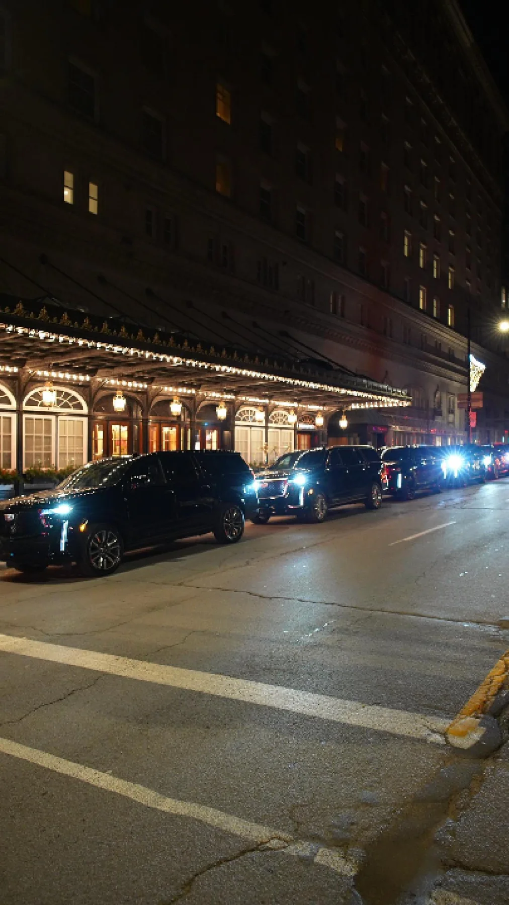 SUV negros frente a la entrada iluminada del Ritz-Carlton de noche.
